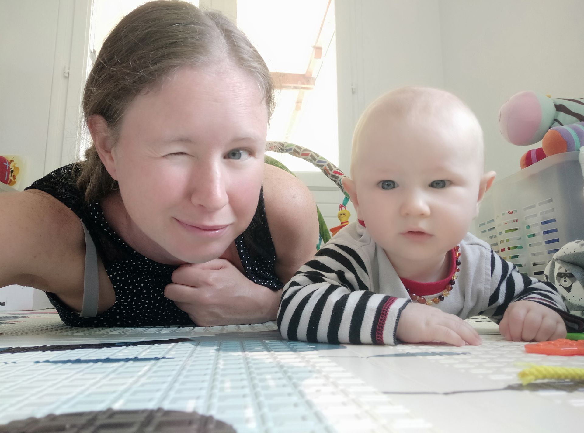 bébé et femme à plat ventre qui font un clin d'oeil bébé et femme à plat ventre qui font un clin d'oeil